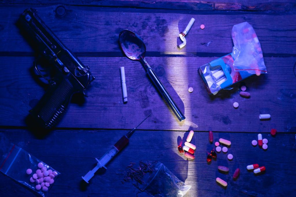 Intriguing still life image depicting pills, a gun, and syringe under dramatic lighting.